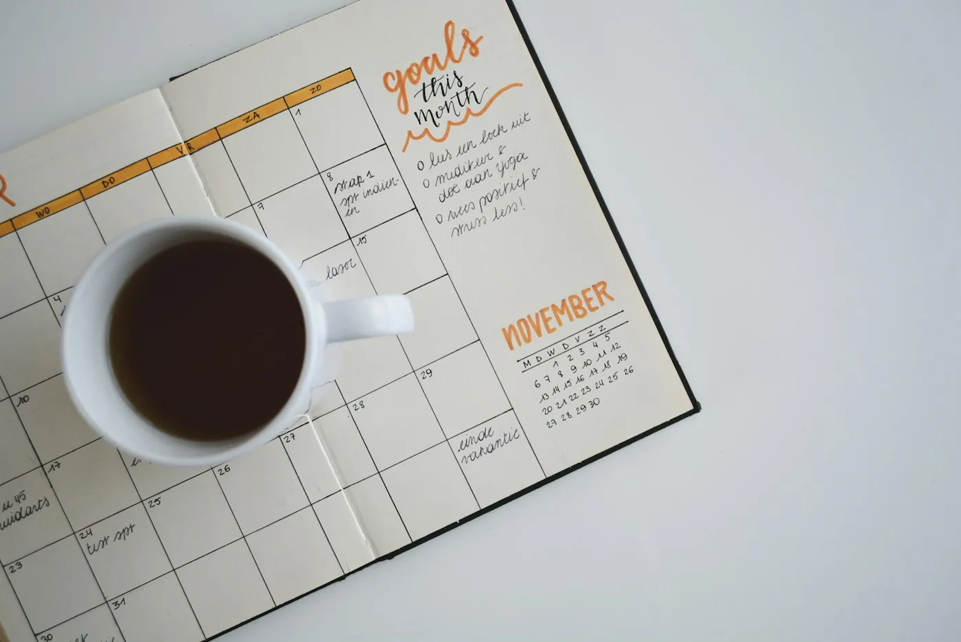 A cup of coffee resting on an open monthly planner