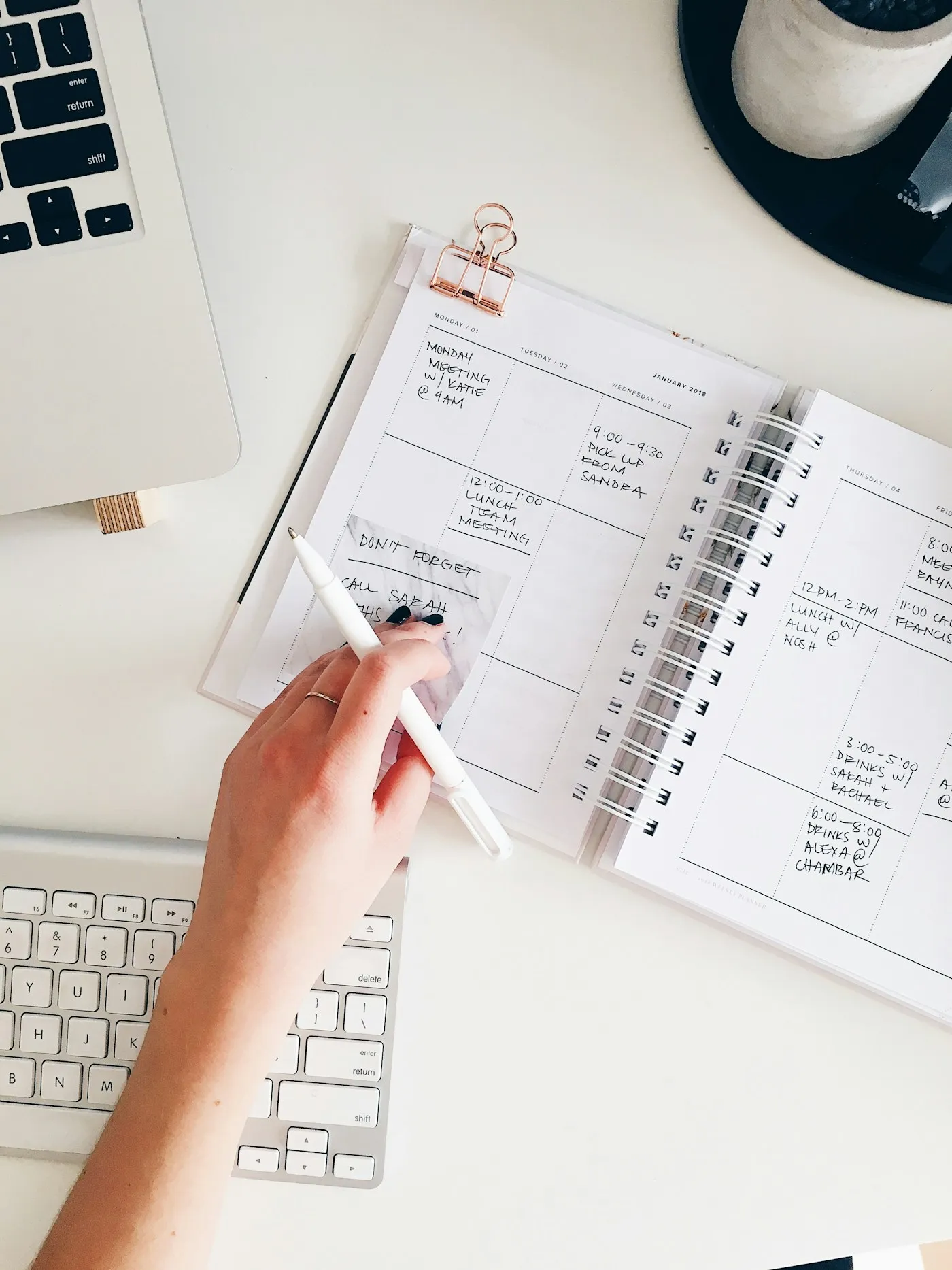 A hand writing notes in a weekly planner